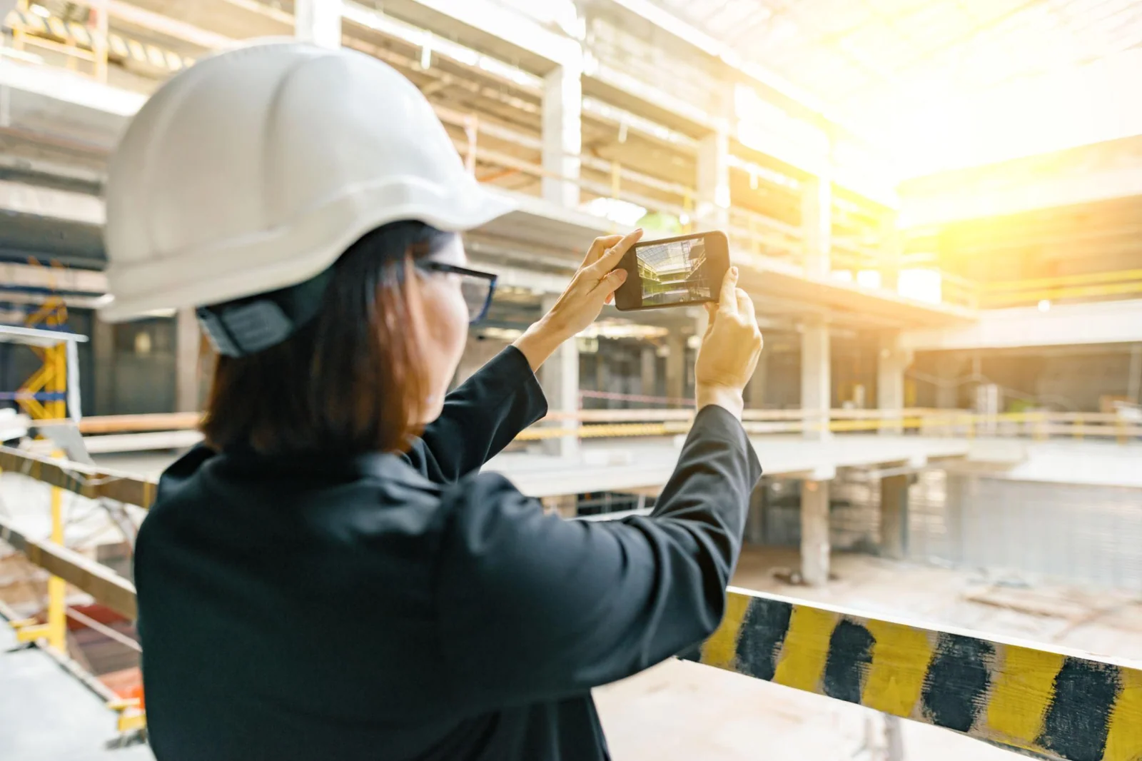 Site professional recording a building with a mobile phone.